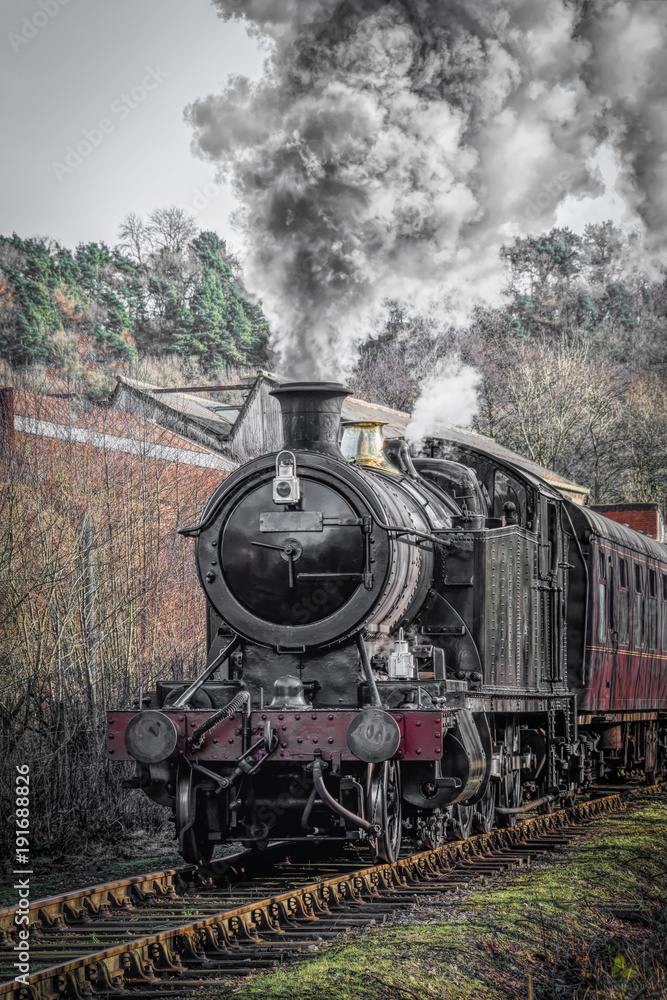 Fototapeta premium Pionowy widok pionowy lokomotywy pociągu parowego w ruchu, zwrócona do przodu i dymiąca