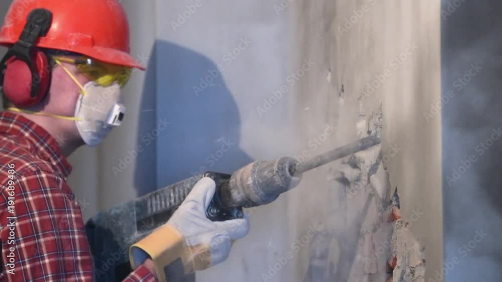 worker with demolition hammer breaking interior wall worker with demolition hammer breaking interior wall