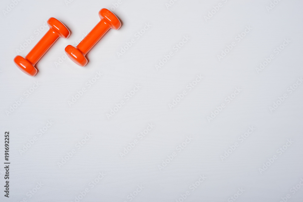 Two dumbbells of orange are lying on a white background with a tree texture Two dumbbells of orange are lying on a white background with a tree texture