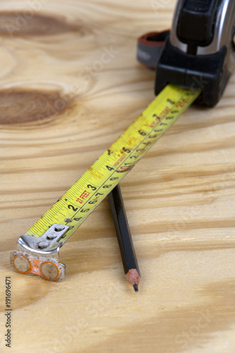 An old well used tape measure and pencil on a pine board