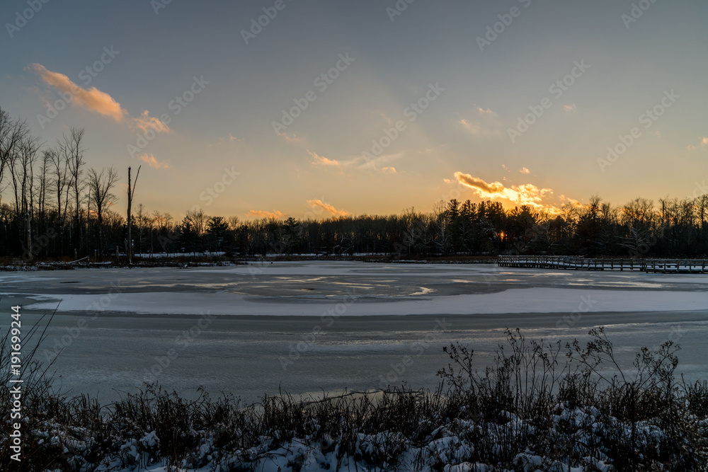 An ice covered Duck Pond in the Park  with a nice sunset.