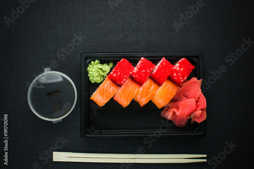 Beautiful rolls in the black container on black background with reflection, for a menu or website photo