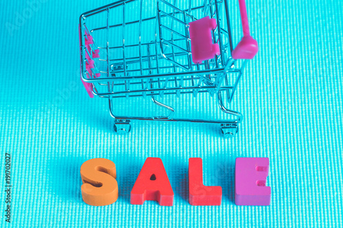 Sale colorful wooden text and shopping cart or supermarket trolley on blue background with copy space, shopping discount and merketing concept. template for add text or photo. photo