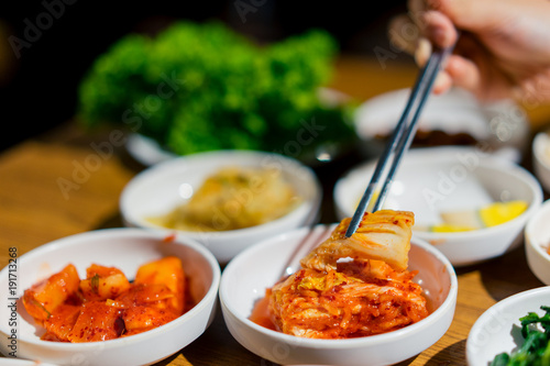Fotografie Woman hand holding chopsticks for eating Kimchi salad in restaurant