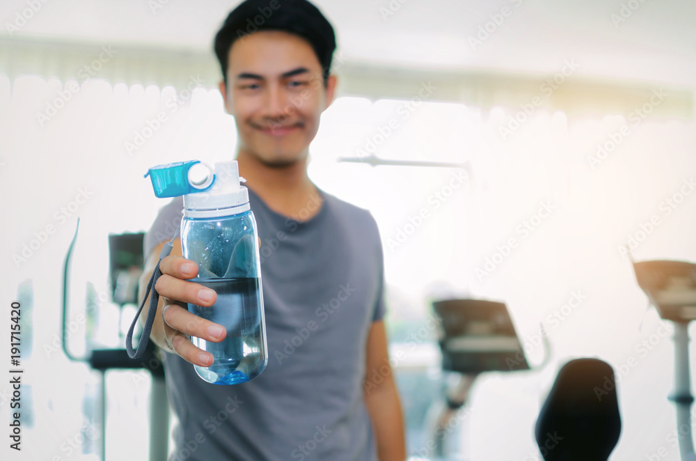 close up hand of muscular handsome man giving blue water bottle while resting after workout for good healthy in fitness gym center, bodybuilder, healthy lifestyle, exercise and sport training concept close up hand of muscular handsome man giving blue water bottle while resting after workout for good healthy in fitness gym center, bodybuilder, healthy lifestyle, exercise and sport training concept