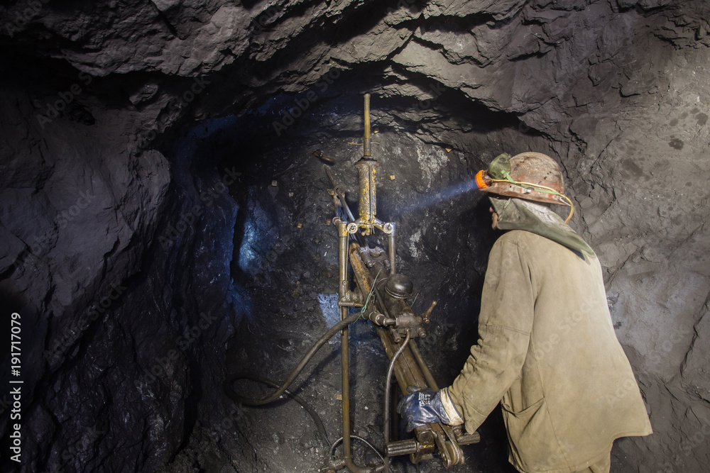 Underground iron ore mine shaft tunnel gallery with miners drilling Underground iron ore mine shaft tunnel gallery with miners drilling