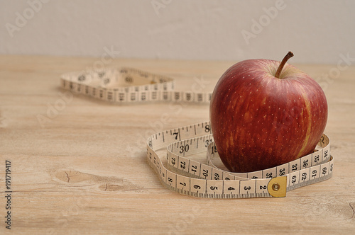 A red apple displayed with a measuring tape