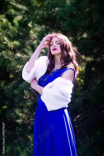 Beautiful fashion model in a dress in a green park in the summer . Blue dress.