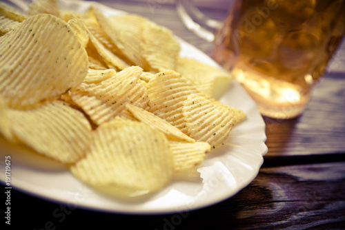 Potato chips and beer on a wooden table 