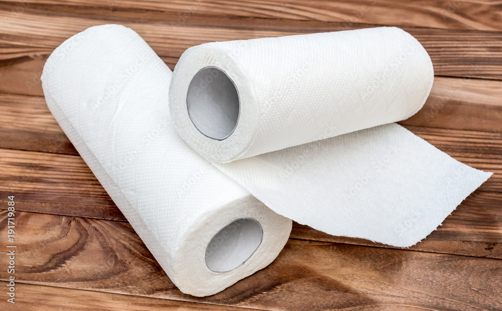 Two paper kitchen towels on the brown wooden table. Two paper kitchen towels on the brown wooden table.