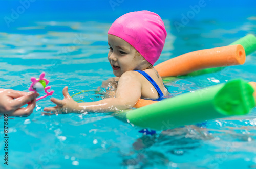 A little girl of European appearance floating in the pool on inflatable toy
