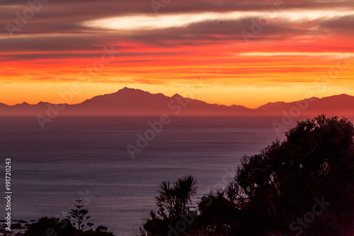 Sunset behind ocean and mountain