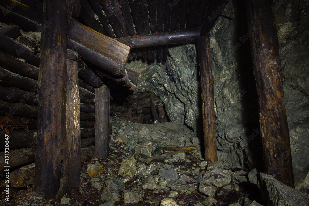 Underground abandoned gold ore mine shaft tunnel gallery with wooden timbering Underground abandoned gold ore mine shaft tunnel gallery with wooden timbering