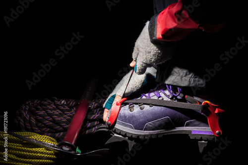 Close up of crampon and plastic boot for mountaineering. Hiking equipment on the glacier, illuminated by the light of a head lamp