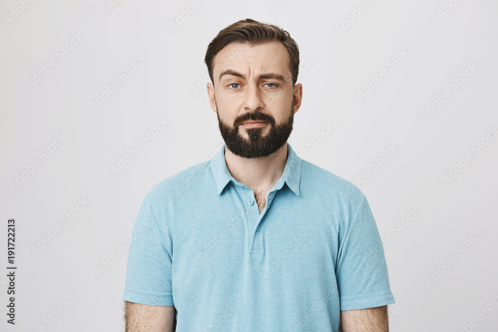 Fototapeta premium Portrait of a mature man with a beard and moustache looking suspicious. Person lifts his eyebrow and do not really believe in the words he hears, looking a little bit gloomy.