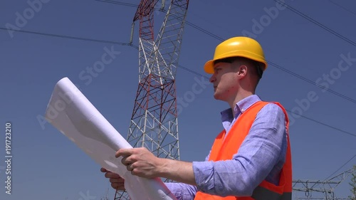 Disappointed upset tired electrician reading energy distribution plan blueprints