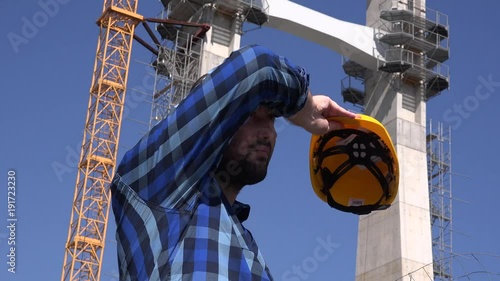 Working outdoors construction worker engineer wiping sweat removing helmet tired