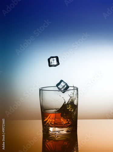 A scotch whiskey glass with splash and ice