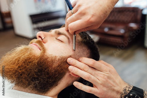 Close up image of barber makes beard cut of a man