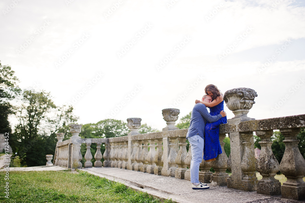 Lovely couple in love against old castle. Girl in blue dress.