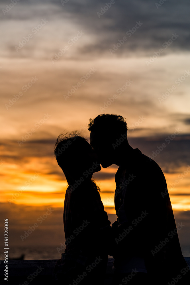 Silhouette couple kissing on the beach with beautiful sunset sky.