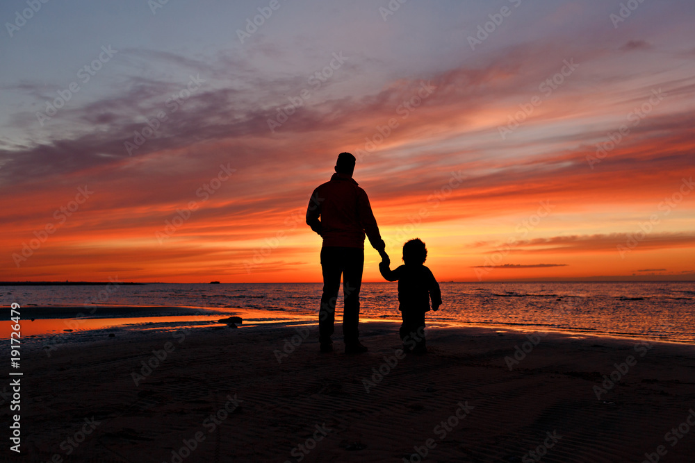 Dad and son are looking on the sunset