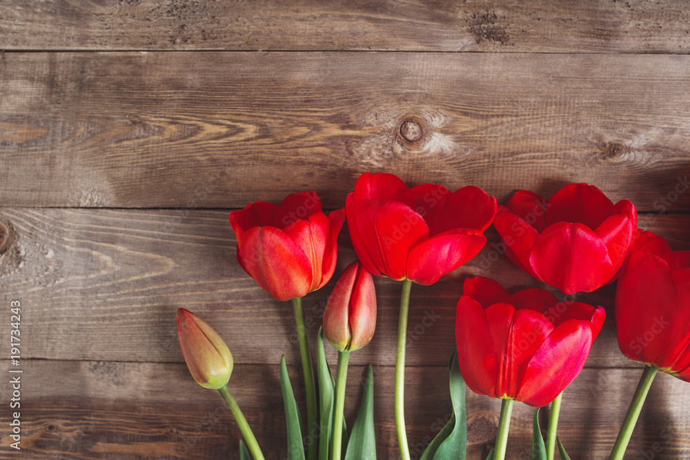 Row of tulips on wooden background with space for message. Mother's Day background.