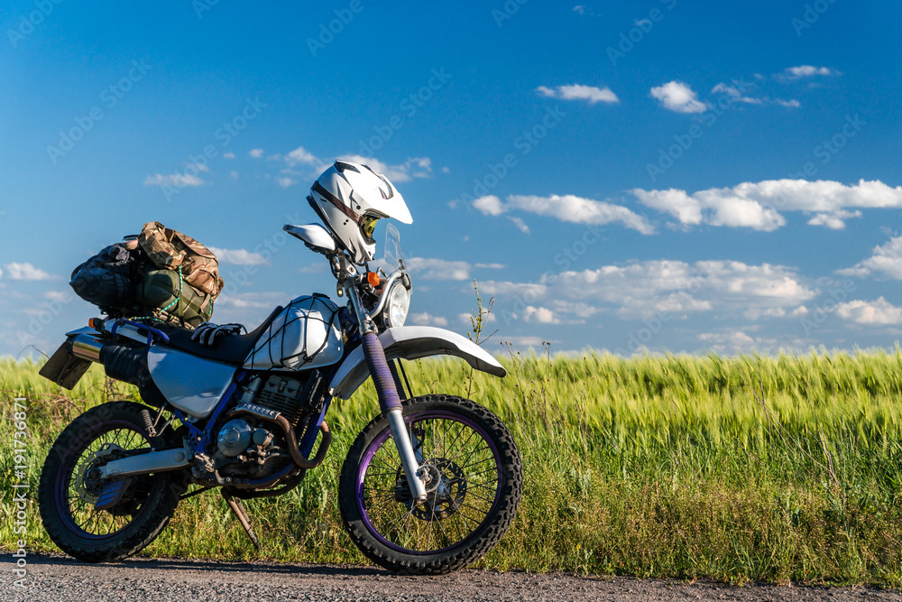 off road dual sport enduro motorcycle on the road between rice fields at sunset, travel concept design