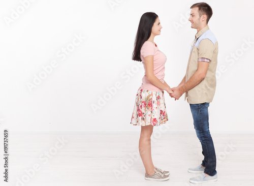 Young couple in love holding hands. Boy and girl hug isolated on white background. Rear view full length. Copy space for template. View from the side of a full-length. Horizontally.