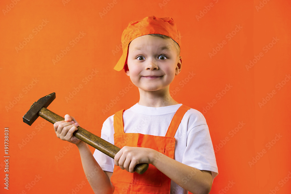 funny builder boy holding a hammer on an orange background funny builder boy holding a hammer on an orange background