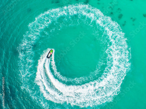 People are playing a jet ski in the sea.Aerial view. Top view.amazing nature background.The color of the water and beautifully bright. Fresh freedom. Adventure day.clear turquoise at tropical beach © MAGNIFIER