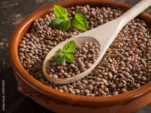 uncooked lentils in a bowl and wooden spoon over black stone. Selective focus