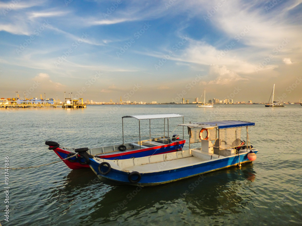 Speed boats at the Clan Jetties of Georgetown with a city view and a dramatic blue sky in the background - Penang, Malaysia