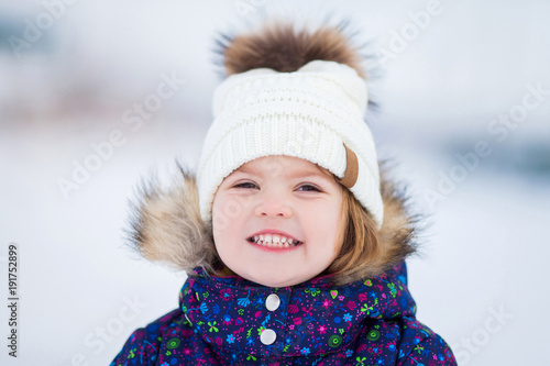 Little cute toddler girl outdoors on a sunny winter day.