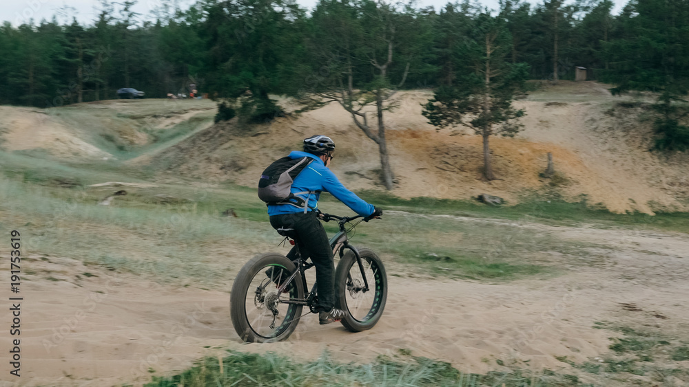 Fat bike also called fatbike or fat-tire bike in summer driving through the hills. The guy is riding a bike along the sand and grass high in the mountains. He performs some tricks and runs dangerously Fat bike also called fatbike or fat-tire bike in summer driving through the hills. The guy is riding a bike along the sand and grass high in the mountains. He performs some tricks and runs dangerously