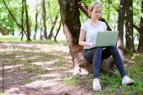 Woman typing on a laptop in the forest photo