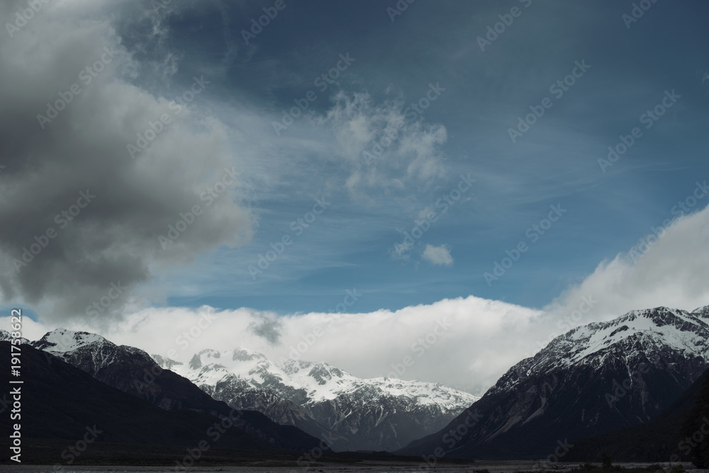 Paisaje de montañas nevadas con cielo azul nuboso.