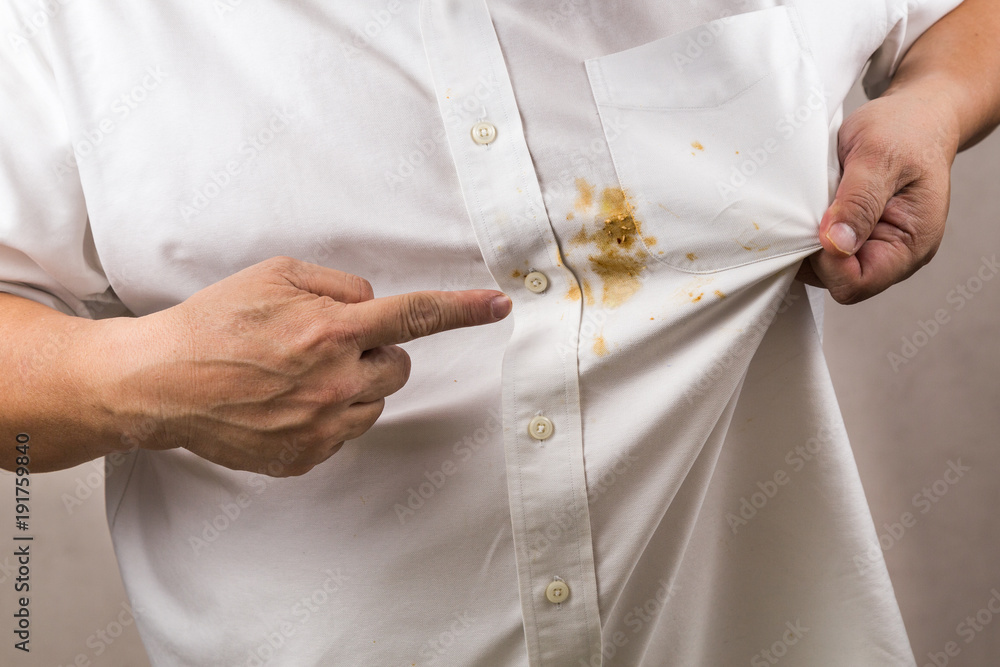 Person pointing to spilled curry stain on white shirt. - obrazy, fototapety, plakaty 