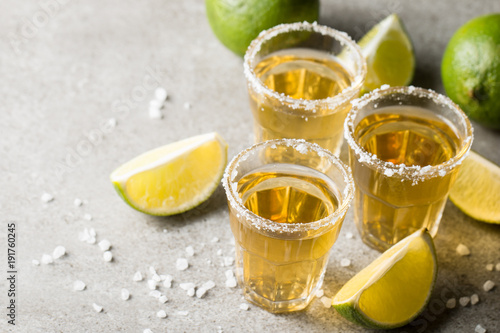 Macro focus photo of shots of golden Mexican tequila with lime and salt on wooden background. Alcoholic drink concept.