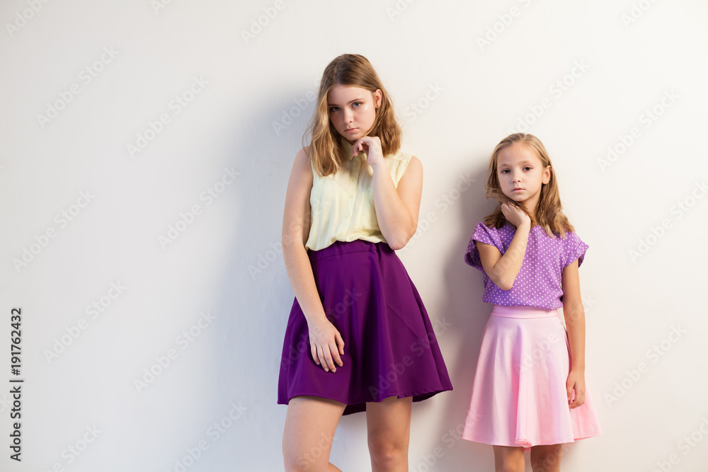 two girls posing with bright fashionable dresses on a white background two girls posing with bright fashionable dresses on a white background