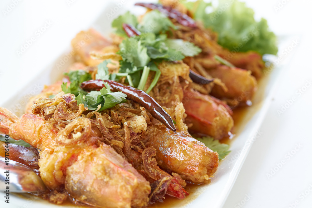 Deep fried prawn with tamarind sauce topping by crispy shallot and dried red chili in white plate on table Deep fried prawn with tamarind sauce topping by crispy shallot and dried red chili in white plate on table