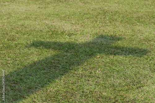 Close up shadow of cross on grass ground
