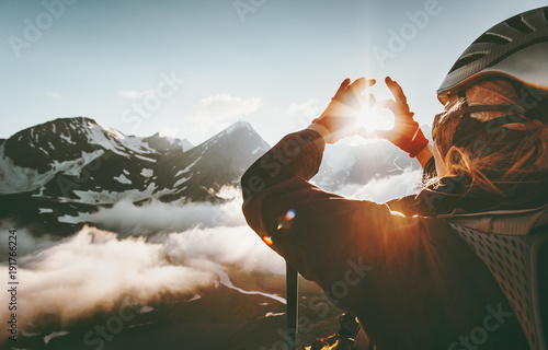 Woman hands Heart symbol shaped Travel Lifestyle and Feelings concept with sunset mountains on background. photo