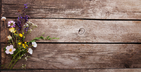 Wild flowers on old grunge wooden background (chamomile lupine dandelions thyme mint bells rape)