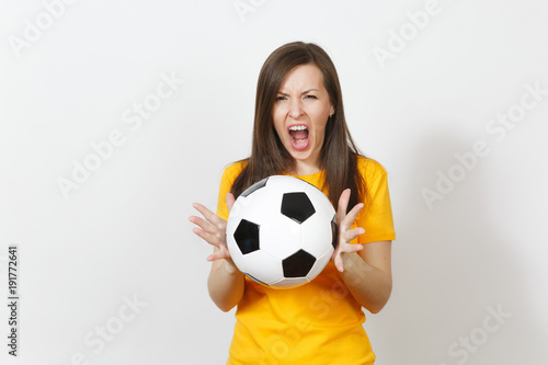 Beautiful European young angry screaming woman  football fan or player in yellow uniform holding soccer ball isolated on white background. Sport  play football  health  healthy lifestyle concept.