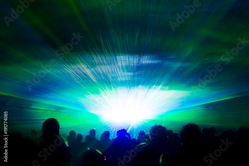 Colorful laser show nightlife hypnosis light tunnel people crowd. Luxury entertainment with audience silhouettes in nightclub event, festival or New Year's Eve. Beams and rays shining colorful lights