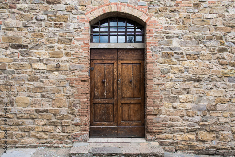 Wooden door with class panel transom in ancient stone wall Wooden door with class panel transom in ancient stone wall