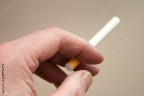 A mans hand holding an unlit cigarette