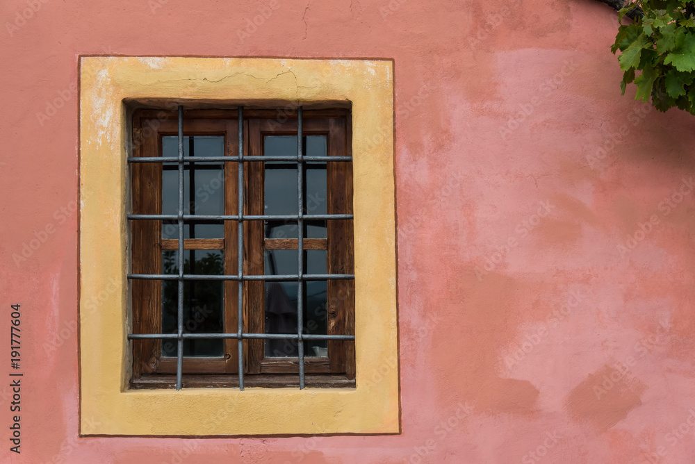 Gated closed window on pink textured wall with yellow frame Gated closed window on pink textured wall with yellow frame