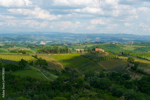 Rolling hills of Tuscany in summer with glowing sunshine and a villa in view